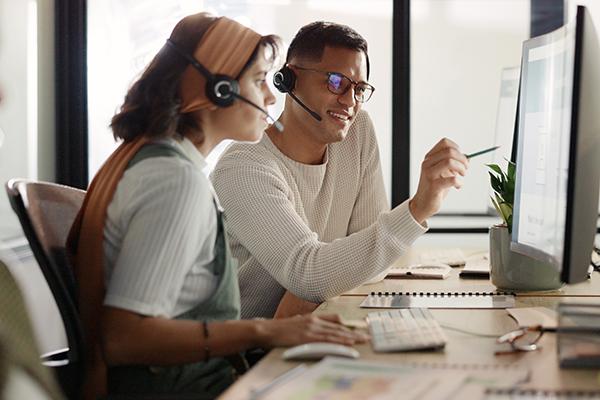 man and woman looking at computer in call center